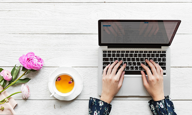 Typing on laptop with flowers and tea